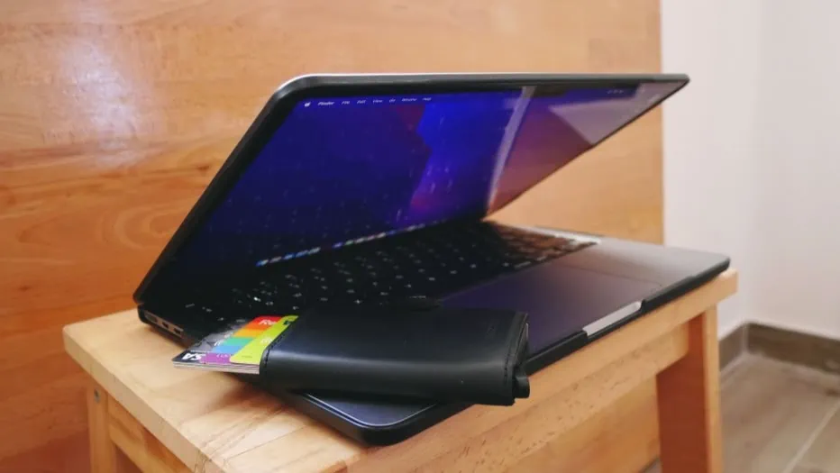 macbook met een portemonnee met bankpasjes erbij op een houten trapje