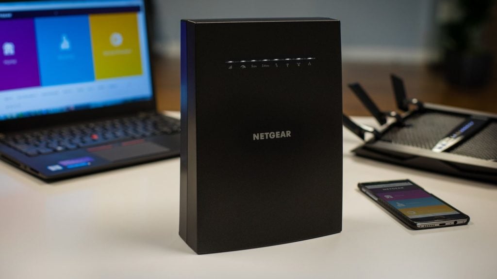 Netgear-Nighthawk-EX8000-op-bureau-met-erachter-een-laptop-en-ernaast-een-telefoon-en-router