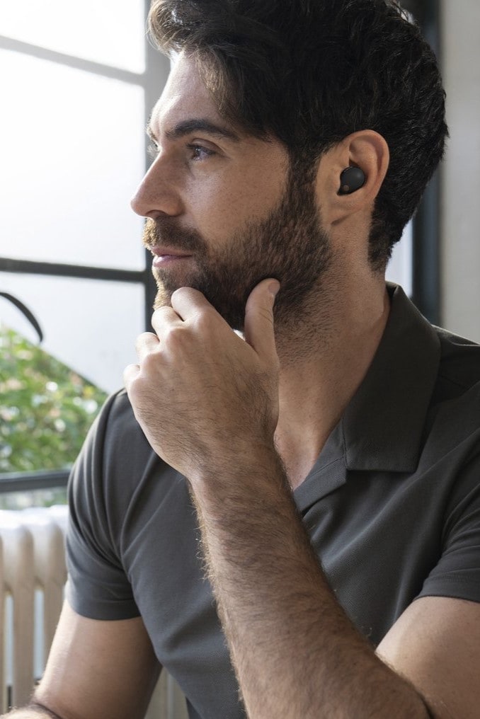 Man kijkt naar buiten en heeft Sony WF-1000XM5 oordopjes in zijn oren