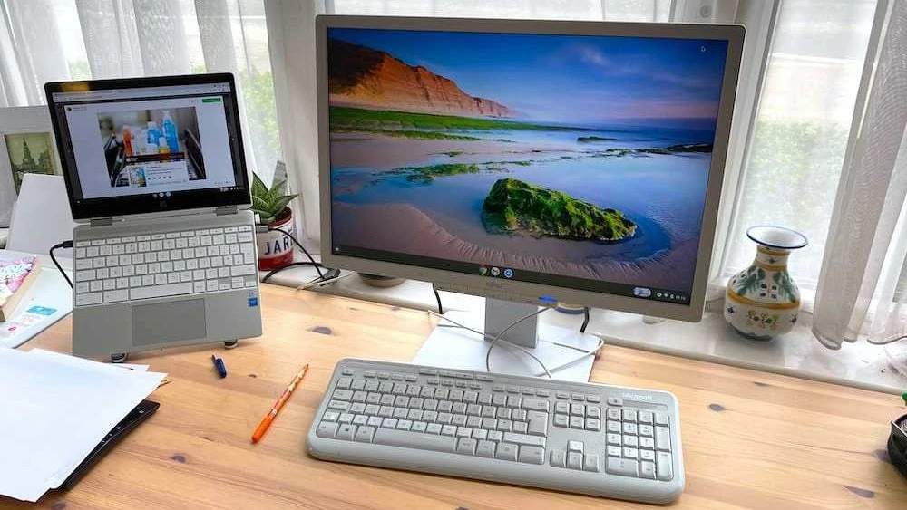 chromebook met tweede beeldscherm ernaast en toetsenbord ervoor op houten bureau
