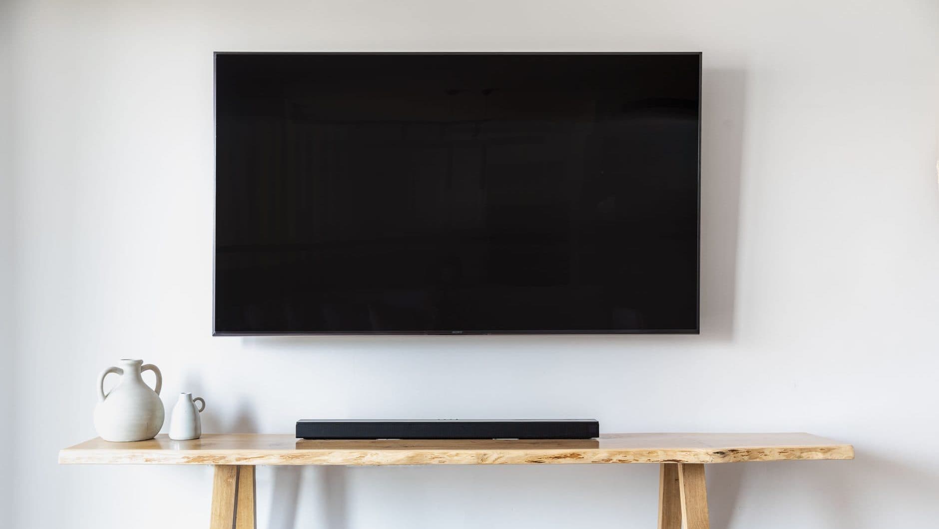 Soundbar op houten tafel onder een televisie in beeld