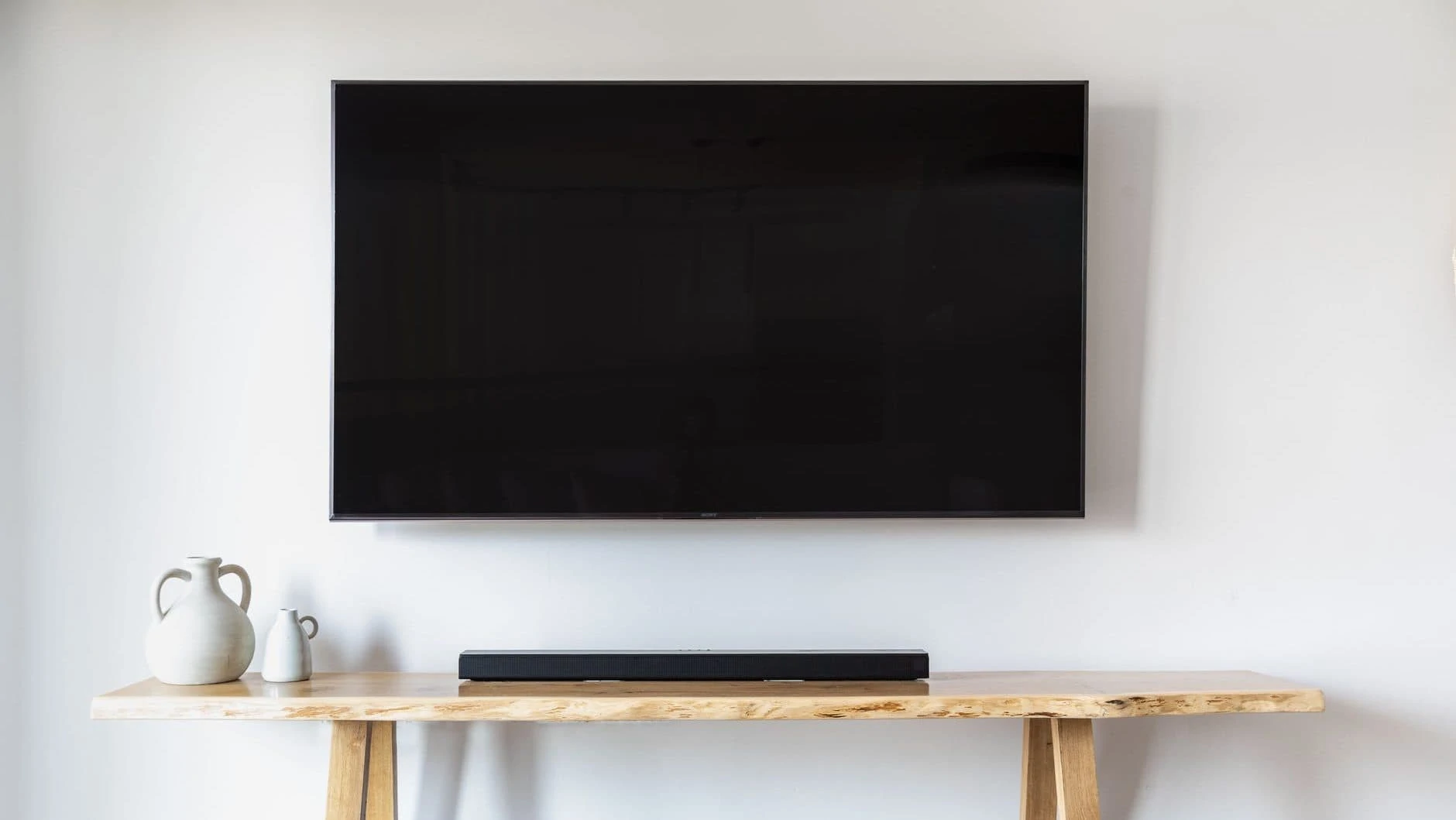 Soundbar op houten tafel onder een televisie in beeld