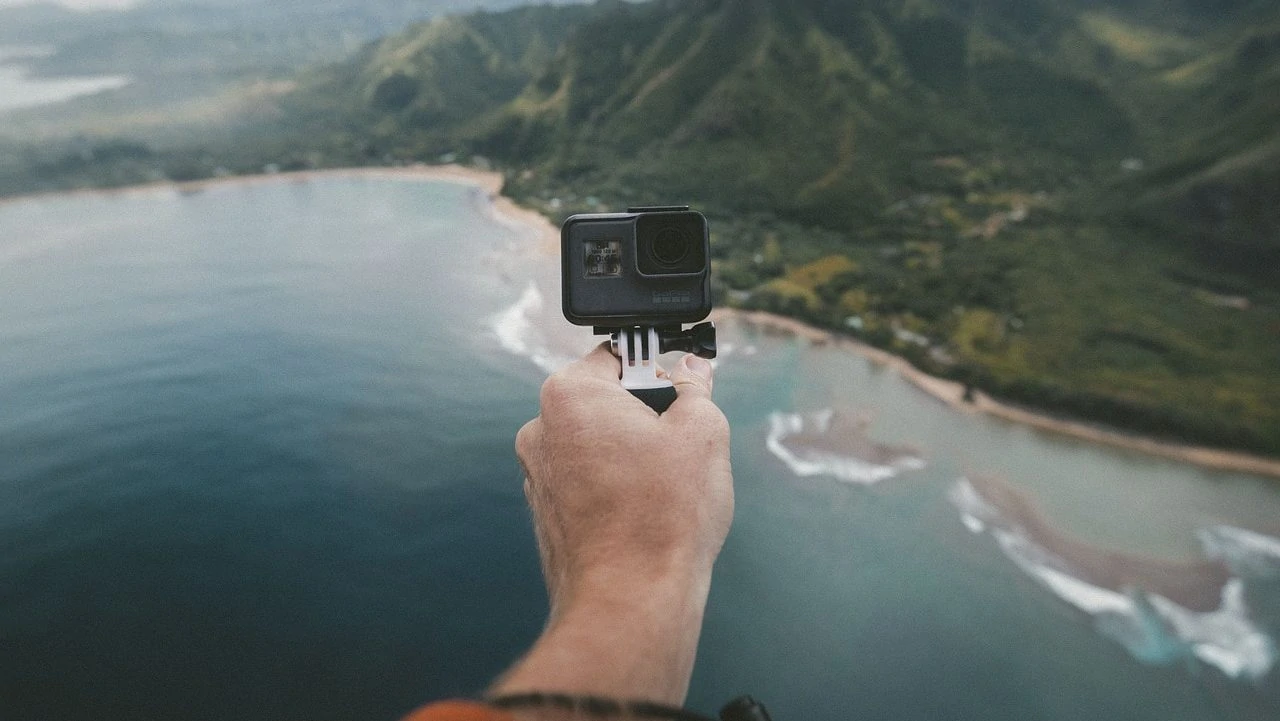 GoPro in hand gericht naar de camera met strand en zee op achtergrond