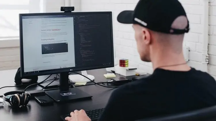 Man werkt op een monitor met twee schermen naast elkaar