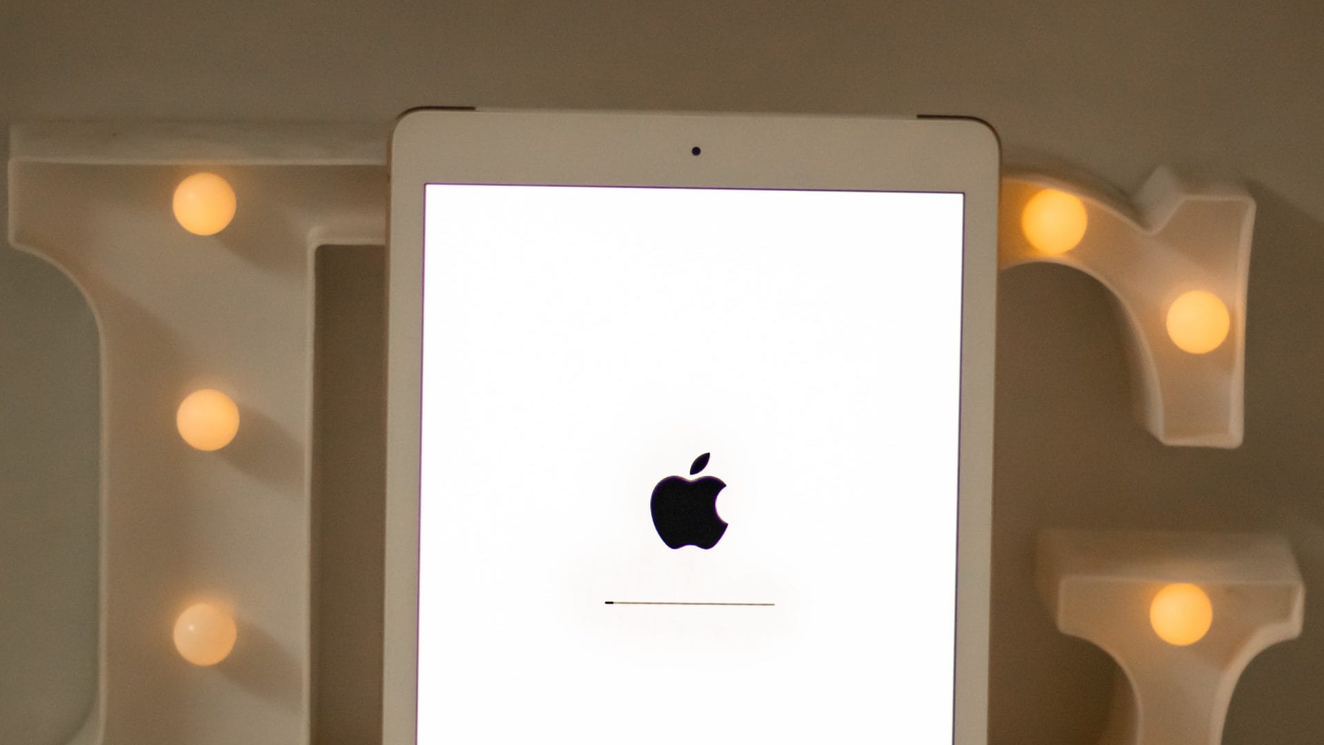 Oudere iPad met zwart Apple-logo op wit scherm en laadbalkje