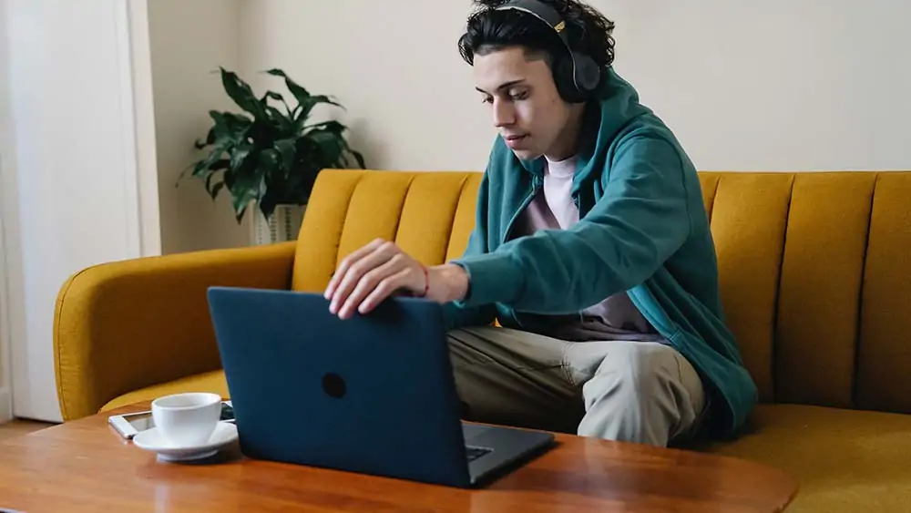 Man met koptelefoon aan zijn laptop