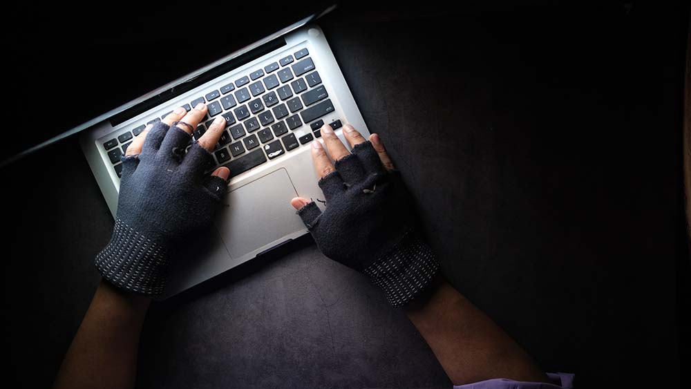 Iemand met vingerloze handschoenen op een MacBook Pro