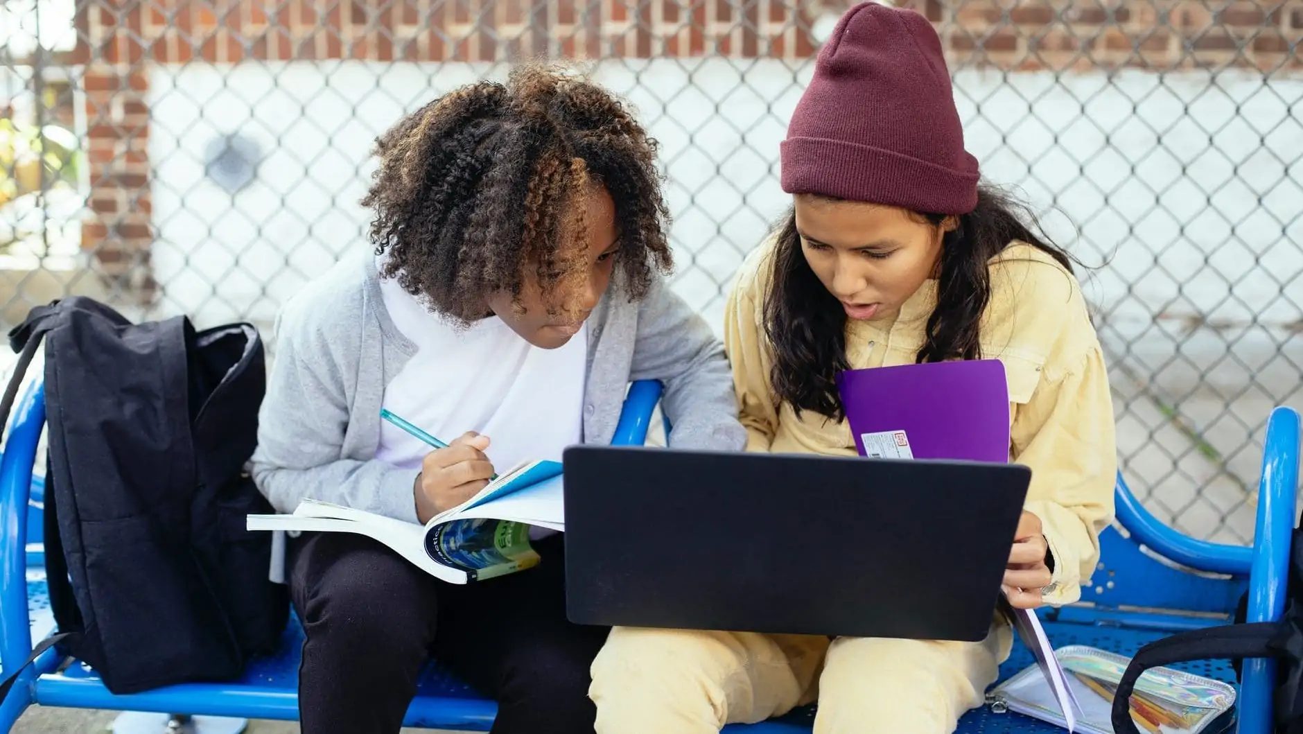 Twee studenten op een bankje met een laptop