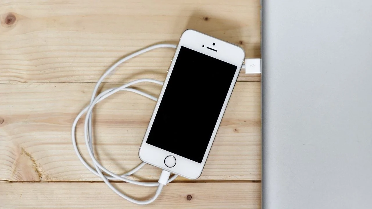 iphone met kabel in macbook op houten ondergrond
