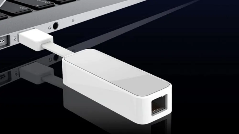 Close-up van een witte ethenet adapter aangesloten op de usb-poort van een laptop