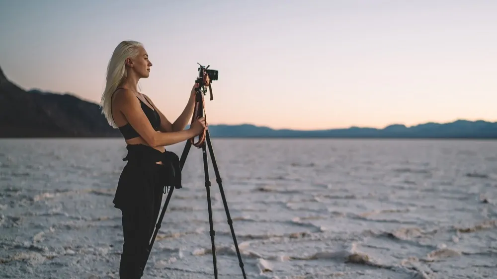 Blonde vrouw in zwarte kleding maakt foto's met een camera op een tripod van een zoutvalkte