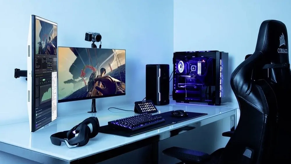 Game-bureaustoel aan een bureau met daarop een pc, twee monitoren, camera, box, headset en toetsenbord voor een game-livestream. Alles in een blauwe tint