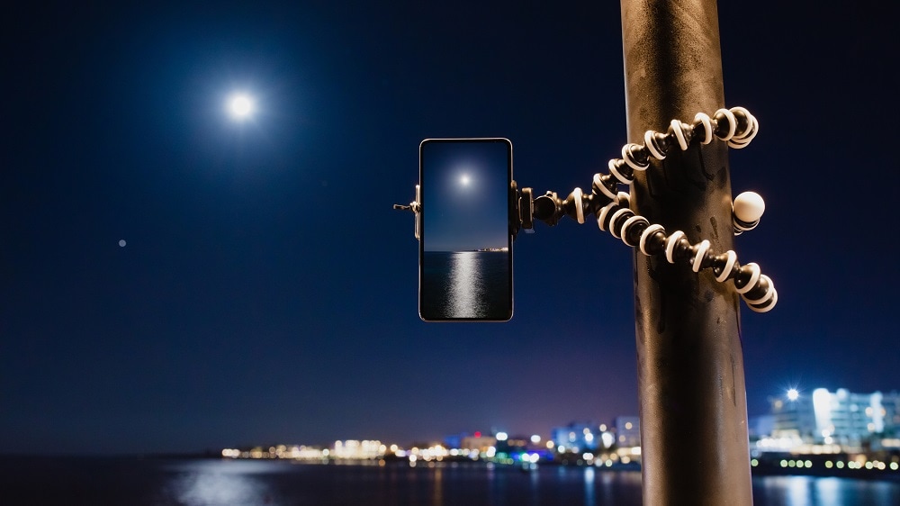 Het gebruik van een smartphone in een gorillapod om een foto van het landschap in de nacht te maken