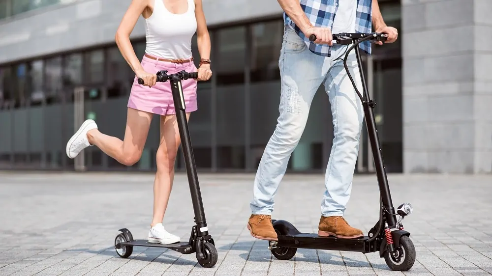 Man en vrouw rijden beide op een zwarte elektrische step. De step van de vrouw is kleiner dan die van de man.