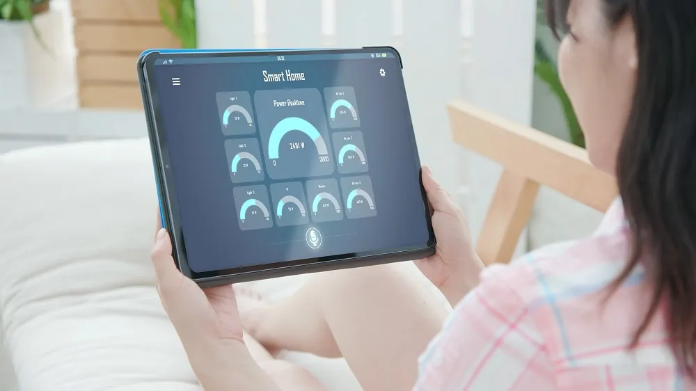 Vrouw gebruikt een app op haar tablet om het energieverbruik van haar slimme apparaten in te zien