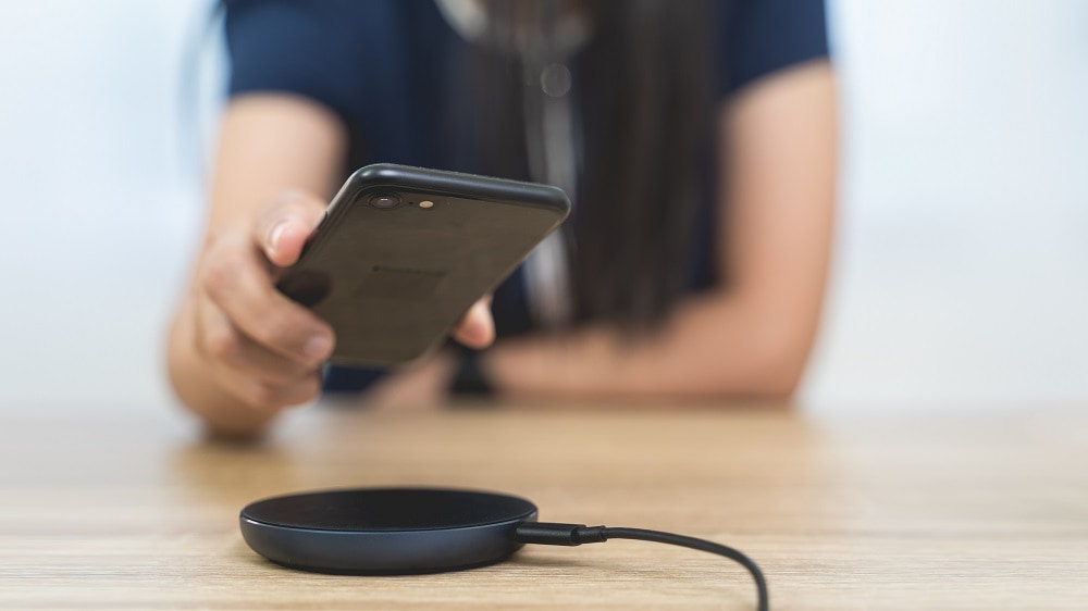 Vrouw legt zwarte iPhone op een zwarte draadloze oplader
