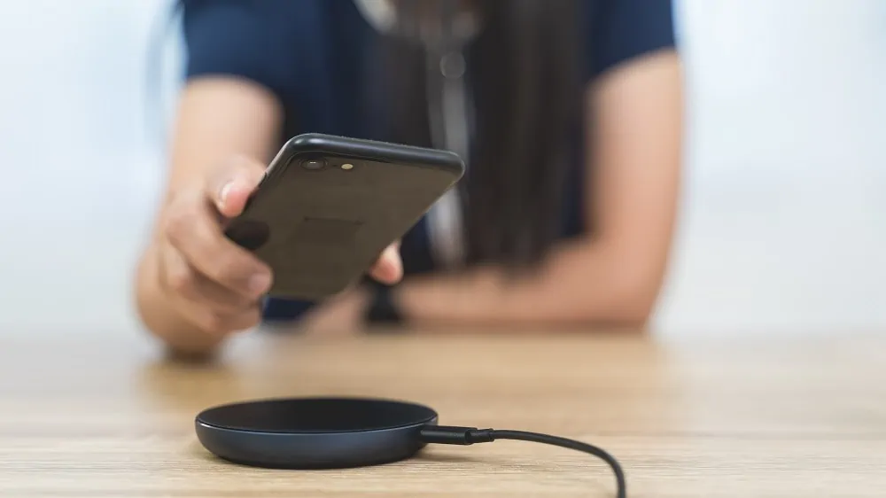 Vrouw legt zwarte iPhone op een zwarte draadloze oplader