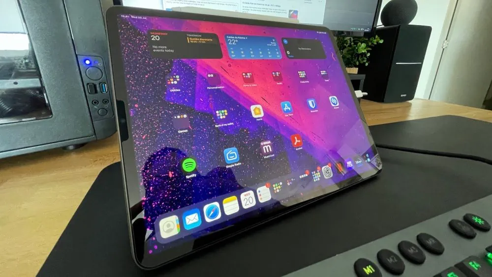 ipad home screen op een bureau met monitor erachter en toetsenbord ervoor
