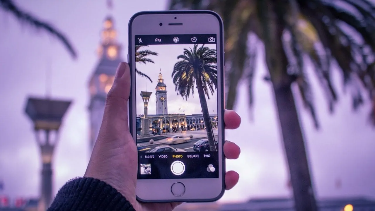 witte iphone maakt foto van gebouw en palmboom