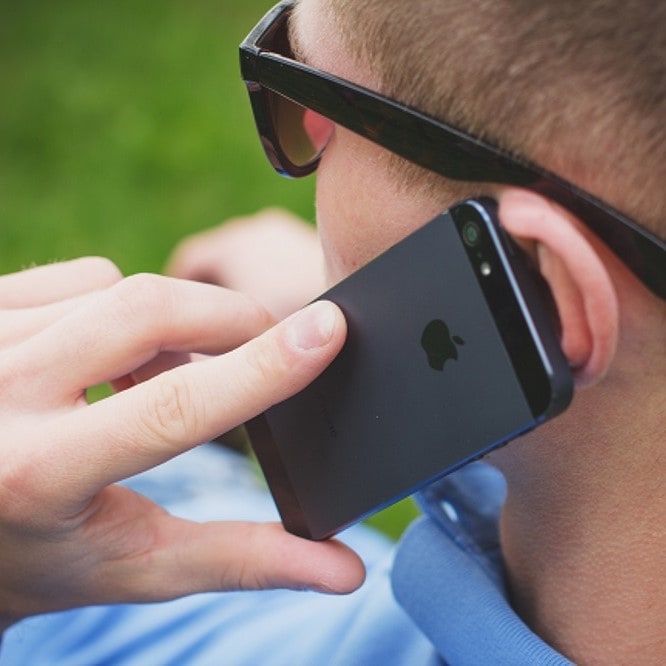 Man met zonnebril belt met een zwarte iPhone