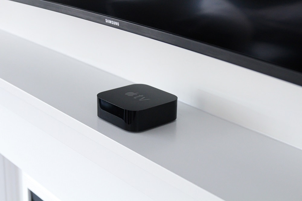 Zwarte Apple TV-box staat op een plank onder een zwarte Samsung tv