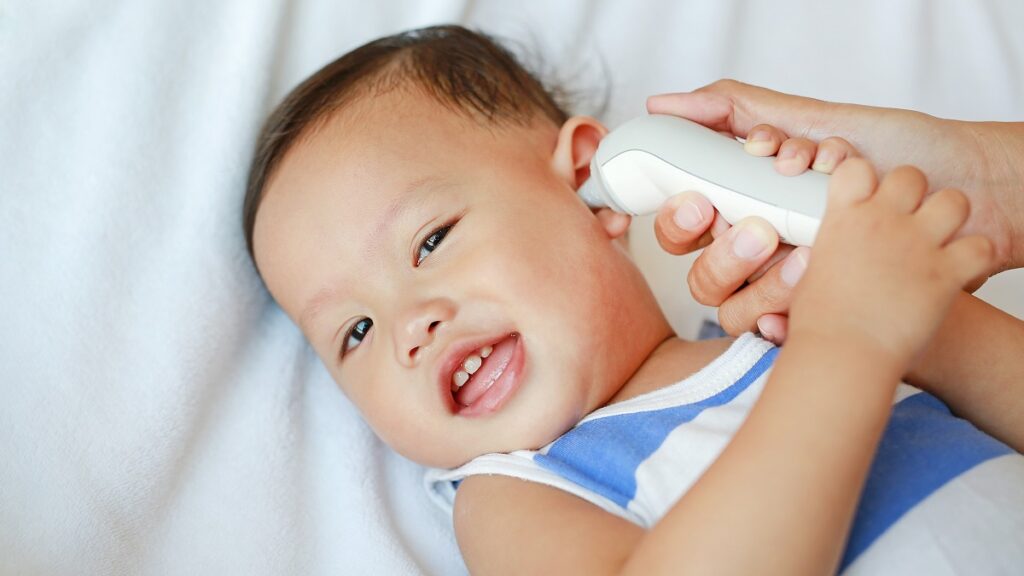 Iemand meet de lichaamstemperatuur van een baby met een oorthermometer
