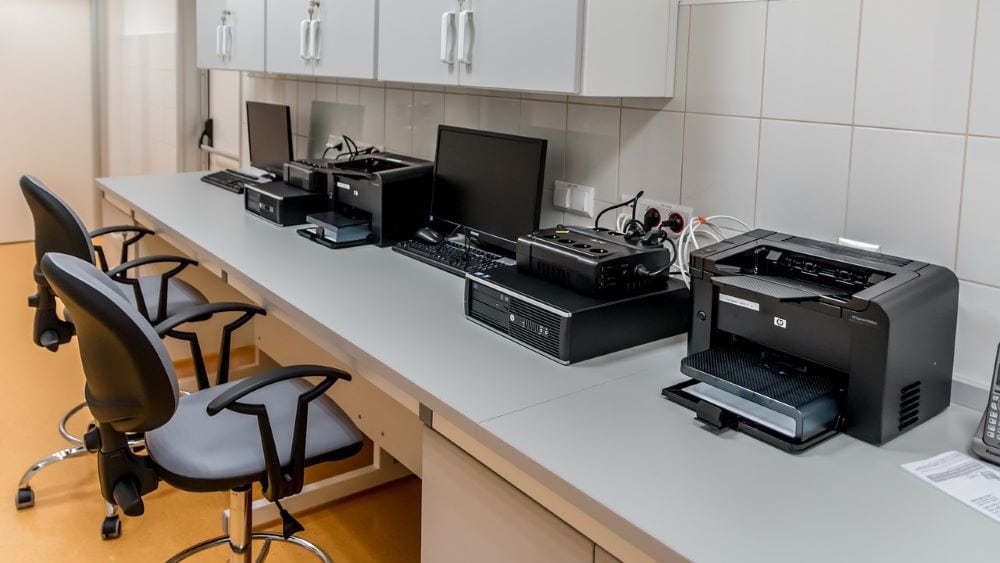 Printers en computers naast elkaar op lang bureau