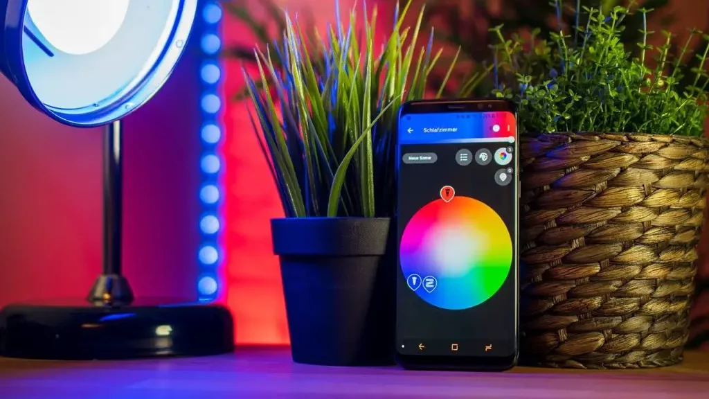 smarthome-app voor lichten op smartphone naast lamp en plant