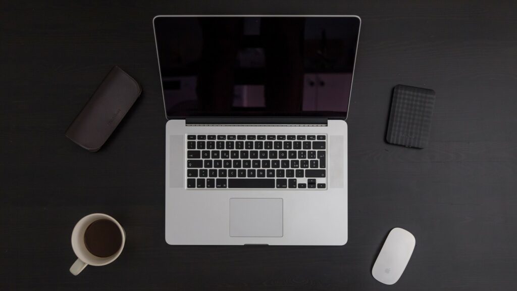 MacBook met daaromheen een harde schijf, koffiekopje, muis en brillenkoker