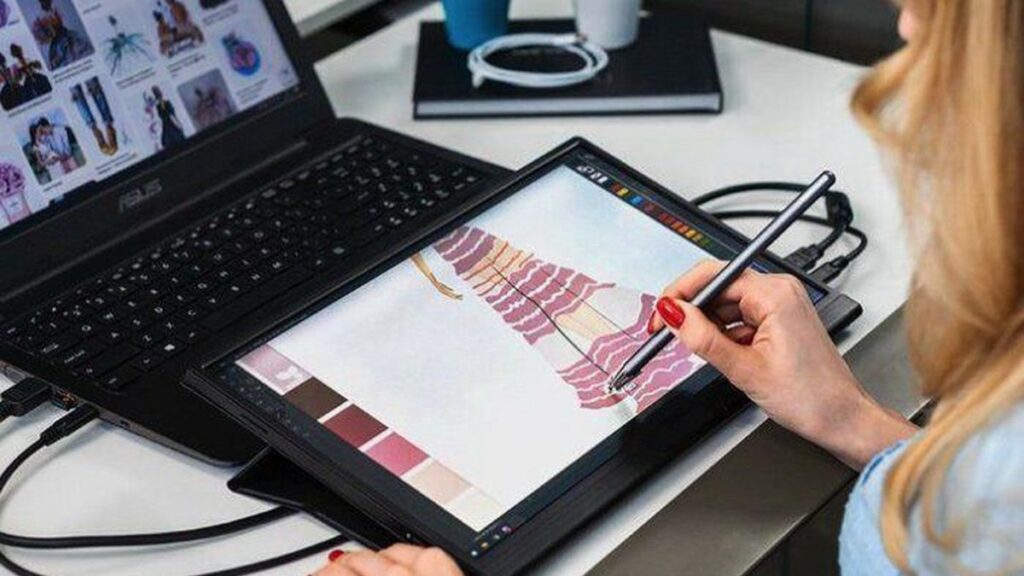 Iemand schetst een tekening op de LOOV FlexDisplay Touch 4k draagbare monitor die aangesloten is op een laptop