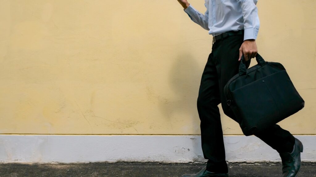 Man in nette kleding loopt met een monitortas in zijn linkerhand