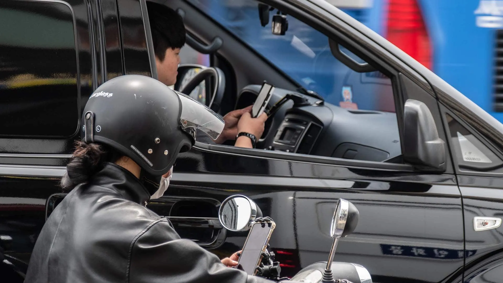 Een motorrijder en de bestuurder van een auto die op hun smartphone kijken